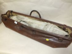 A VINTAGE LEATHER CRICKET BAG CONTAINING A PAIR OF CRICKET PADS AND A BALL