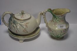 A BELLEEK TEAPOT, A BELLEEK JUG BOTH WITH BLACK MARKS TO BASE AND A TEAPOT STAND, NO MARK