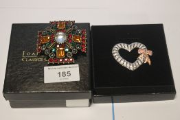 JOAN RIVERS TWO BOXED BROOCHES, A GEM SET CROSS AND A HEART WITH BOW