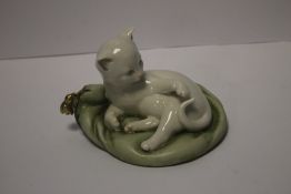 A HAND PAINTED PORCELAIN FIGURE IN THE FORM OF A CAT ON A PART GILDED CUSHION