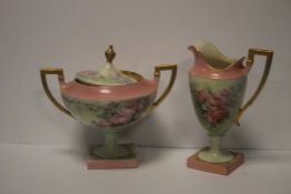 A BELLEEK TWIN HANDLED LIDDED VASE WITH PINK ROSE DECORATION TOGETHER WITH A SIMILAR JUG