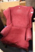 A RED UPHOLSTERED WING BACK ARMCHAIR