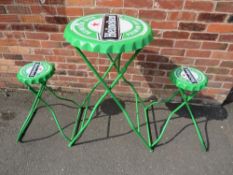A MODERN 'HEINEKEN BEER' METAL FOLDING TABLE AND TWO STOOLS IN THE STYLE OF BOTTLE TOPS