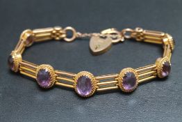 A 9CT GOLD THREE BAR GRADUATING AMETHYST SET GATE BRACELET, set with seven graduating oval