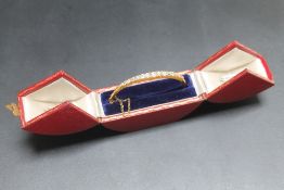 AN 18CT GOLD GRADUATED DIAMOND BANGLE, set with seventeen brilliant cut diamonds of a good colour,