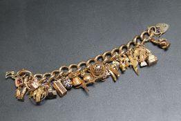 A YELLOW METAL BRACELET WITH MANY CHARMS, to include an enamelled egg, approx weight 105g
