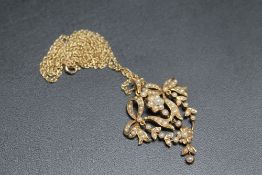 AN ANTIQUE TYPE 15CT GOLD SEED PEARL ARTICULATED PENDANT, in a bow and flower design and on