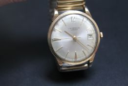 A VINTAGE J W BENSON GOLD DATE WATCH, probably 9 carat, on expandable plated bracelet,