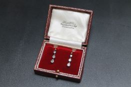 A PAIR OF THREE STONE DIAMOND DROP EARRINGS, each set with three graduating diamonds totalling an