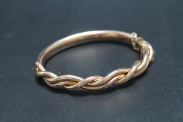 A GOLD AND COPPER BANGLE, having old repair with the three strand intertwined upper section having a