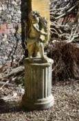 A sculpted limestone garden model of a putto clutching a sheaf of wheat