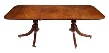 A mahogany twin pedestal dining table with one loose leaf in Regency style
