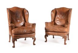 A PAIR OF WALNUT AND LEATHER UPHOLSTERED WING ARMCHAIRS, IN GEORGE II STYLE