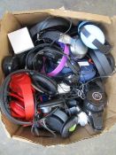 A box of assorted pre-owned over-ear headphones.
