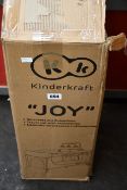 A boxed Kinderkraft Joy Travel Cot with accessories in pink.