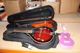 A Stagg ukulele, a Gears4music violin in case and a Gigsby mandolin in a case.