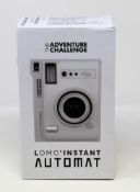 A boxed as new The Adventure Challenge & Lomography Lomo Automat Instant Camera (Box opened).