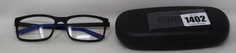 Three pairs of as new Puma black framed glasses with blue tips to arms with cases (Clear lenses).