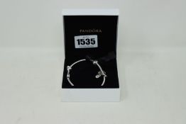 An as new Pandora charm bracelet with three charms.