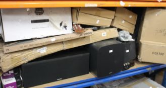 A shelf of music and related items to include drum pads, speakers and mic stands.