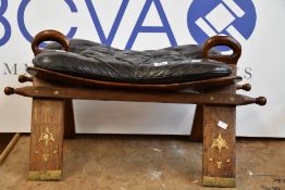 A pre-owned vintage camel saddle stool.