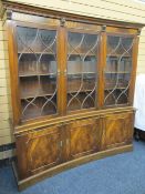 MAHOGANY CONCAVE REPRODUCTION BOOKCASE with dentil shaped cornice, over three upper glazed doors