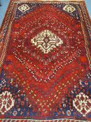 AN EASTERN STYLE RED GROUND WOOLLEN CARPET with central light colour block on a red ground with blue