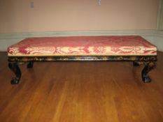 A LONG STOOL in a black lacquered chinoiserie frame on ball and claw corner supports and with red