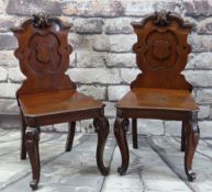 PAIR OF VICTORIAN WALNUT HALL CHAIRS, carved shield backs, solid seats and scrolled legs, 94cms high