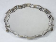 A SMALL SILVER CIRCULAR LETTER TRAY - uninscribed with wavy border on three scroll supports,