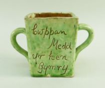 A EWENNY SLIPWARE POTTERY TWIN HANDLED MEAD CUP square based, mottled lime green glaze, with