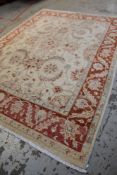 PERSIAN-STYLE IVORY & CORAL RUG, pale floral field within coral border of palmettes and serrated