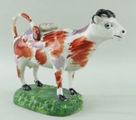 SWANSEA PEARLWARE COW CREAMER standing over a grassy rectangular base, iron-red and pink lustre