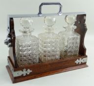 EDWARDIAN OAK TANTALUS, with plated clasps and side lock (no key), with three square spirit