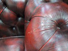 A traditional oxblood red leather three seater chesterfield settee