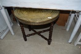 An Indian brass table on folding barley twist wood frame, diameter approx. 60cm