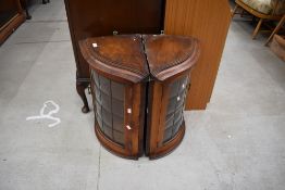 A pair of early 20th Century oak wall corner displays having serpentine fronts and leaded glass,