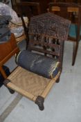 An ethnic style low recliner chair having carved frame, strung seat and additional jewelled style