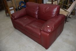 A modern burgundy leatherette two seater settee, width approx. 160cm
