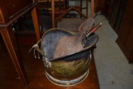 A traditional brass coal helmet and selection of fire tools, including bellows