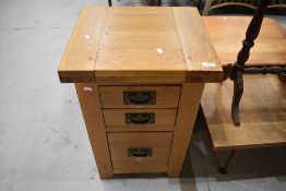 A modern golden oak bedside chest