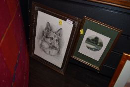 A framed Alsatian print and small signed painting of a cottage in woodland.