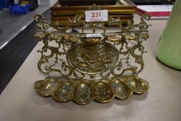 A vintage brass pipe rack with hunting scene of hound and fox to middle.
