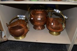 Three copper and brass coal helmets, two having patterned ceramic handles and the other wooden