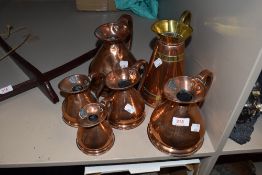 A collection of five antique graded copper measures.1/2 Gill up to a Quart.similar brass and
