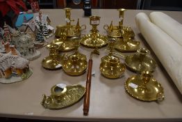 A collection of thirteen brass candle stick holder and a snuffer, some having unusual detailing