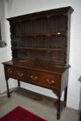 A traditional dark oak dresser having open base, two deep drawers and boarded plate rack