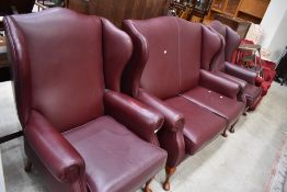 A modern three piece wing back lounge suite , in wine red leather
