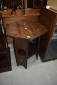 An Arts and Crafts style dark oak occasional hexagonal table, having arch and heart motifs to