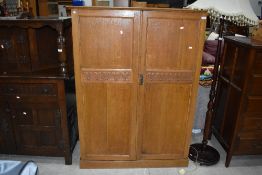 An Arts and Crafts style golden oak compactum style wardrobe, having carved heart motifs to doors,